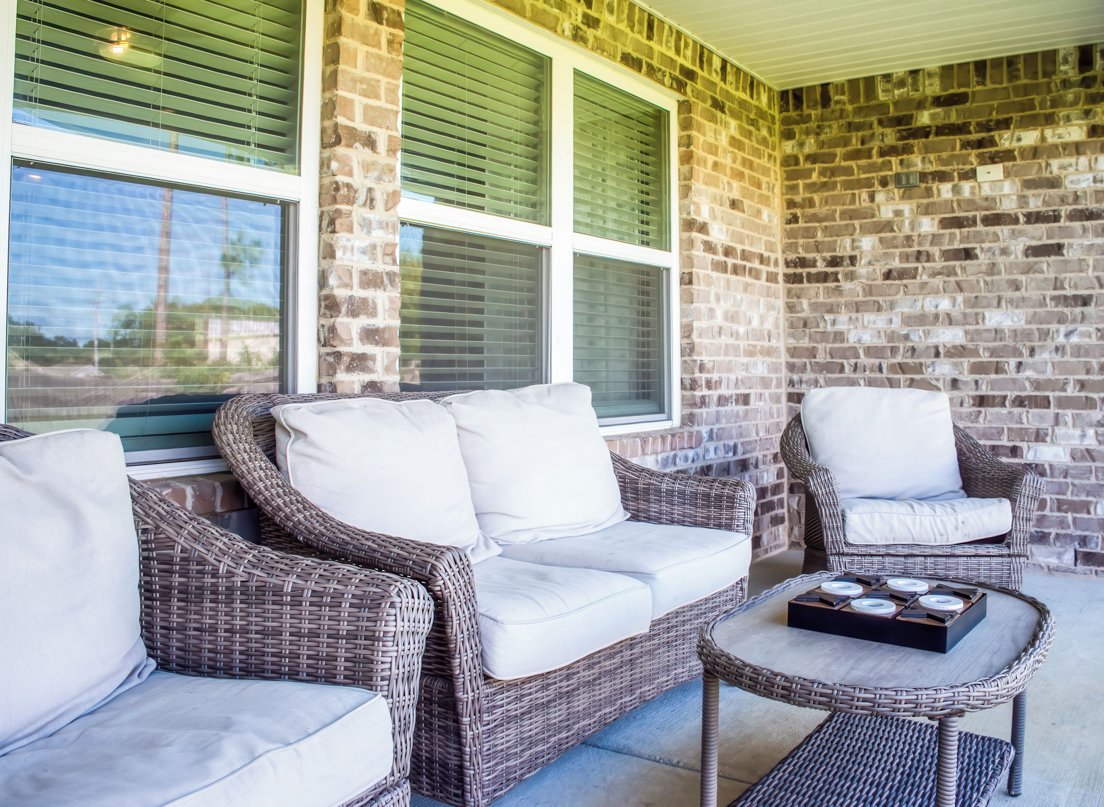 A covered outdoor seating area with wicker furniture and a table with a tray of items.