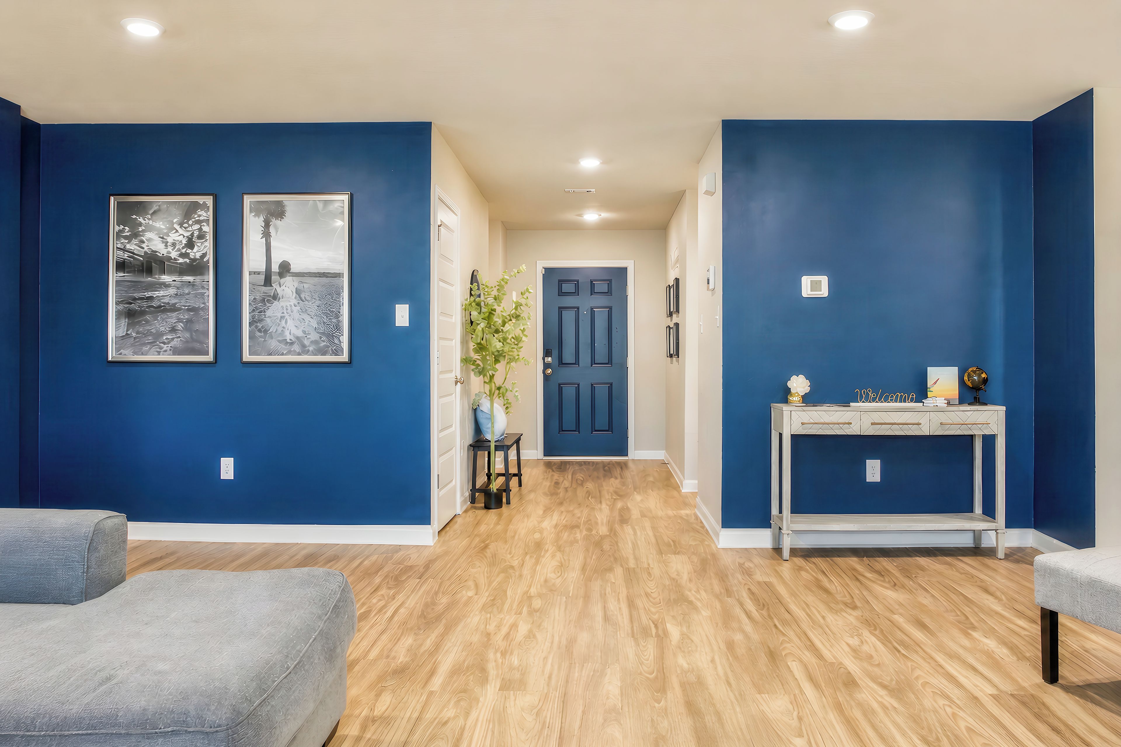 A hallway with blue walls, wooden flooring, a door, and a small table with a globe and a sign.
