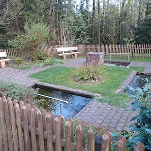 A garden with a wooden fence, a bench, a small pond, and a brick structure. - Apartment '2' with Shared Terrace, Shared Garden and Wi-Fi (Goslar)