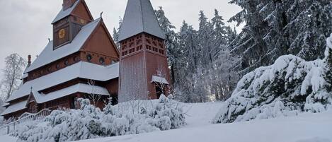 A snow-covered church with a traditional architectural style, surrounded by snow-laden trees.