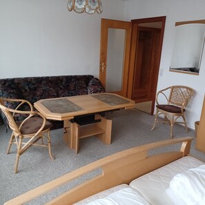 Quarto com cama, sofá, mesa e duas cadeiras.