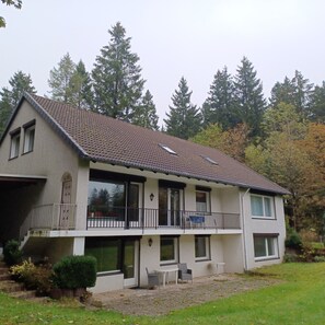 Ein zweistöckiges Haus mit Balkon, großen Fenstern und Garage.