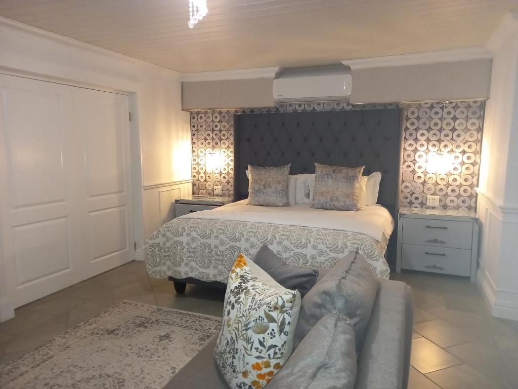 A bedroom with a bed, bedside tables, a nightstand, a patterned rug, and a wall-mounted air conditioner.
