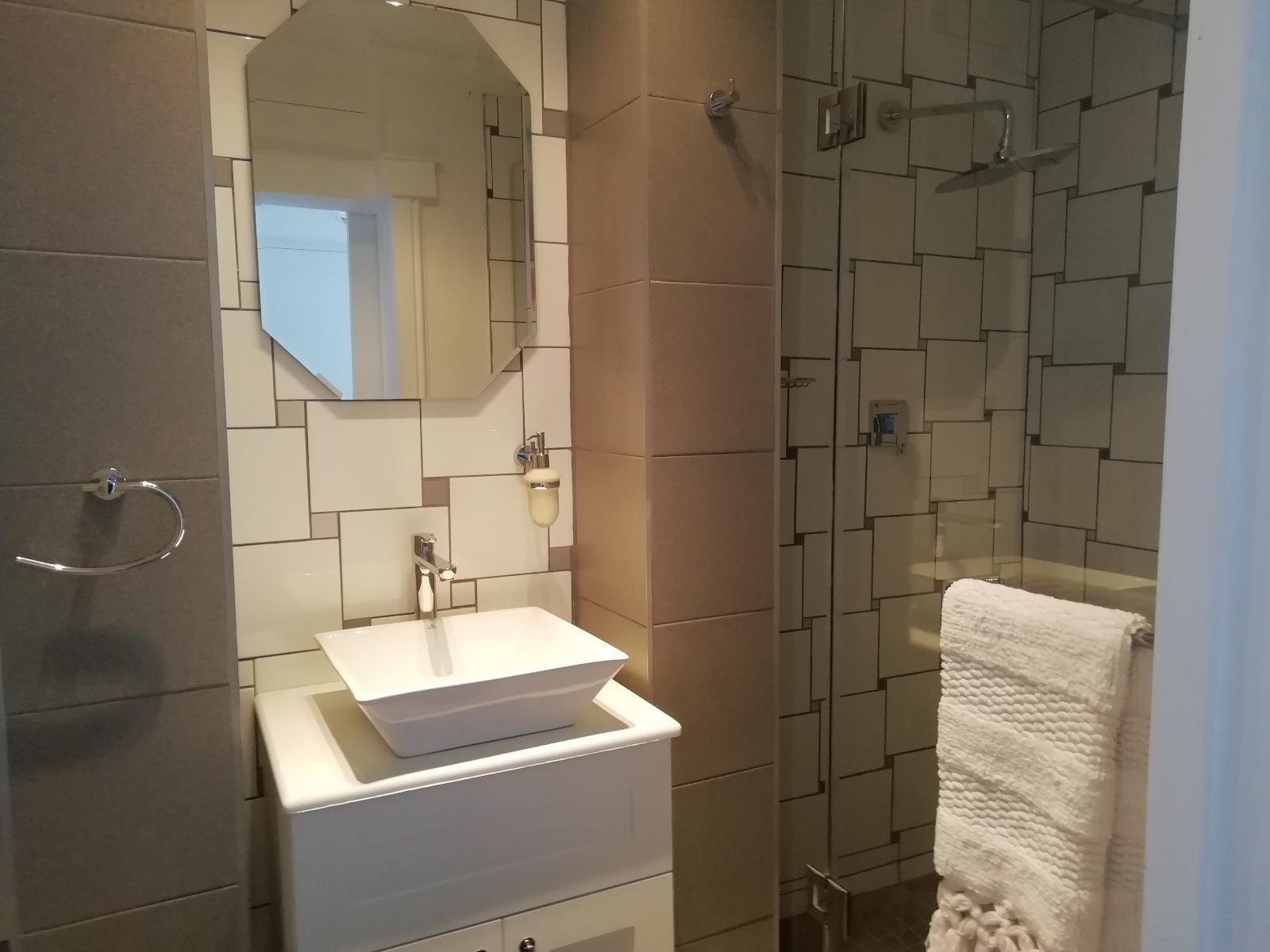 A bathroom with a white sink, a mirror, and a shower area.