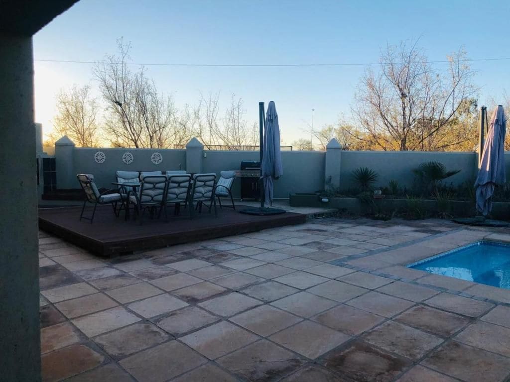 A patio area with a pool, outdoor seating, and a wall with decorative elements.