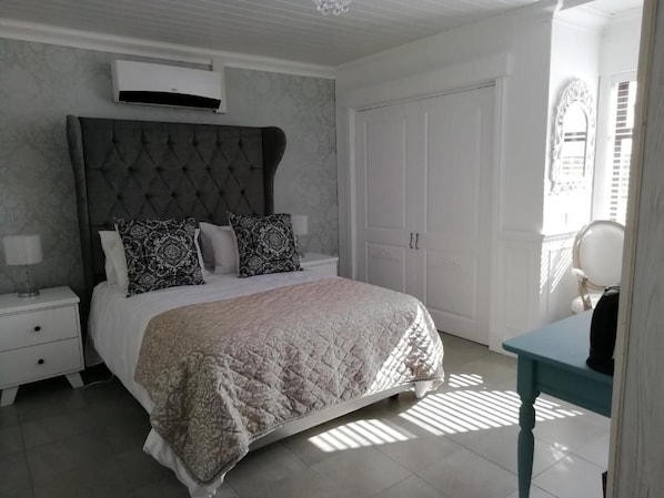 Une chambre avec un grand lit, une table de chevet avec une lampe, une armoire et une petite table avec une chaise.