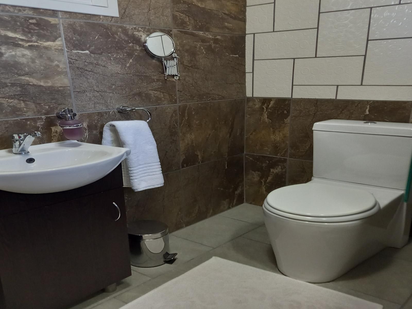 Un baño con lavamanos, inodoro y espejo.