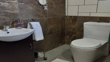 Un baño con lavamanos, inodoro y espejo.