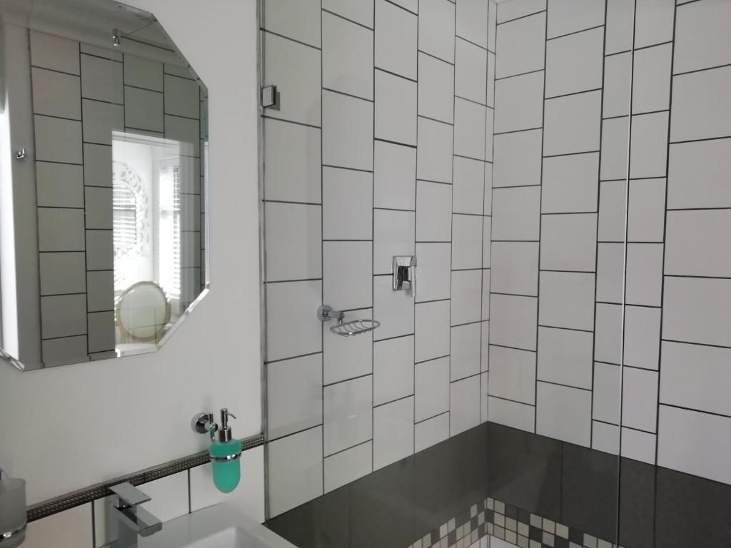 A bathroom with a mirror, a sink, and a shower area.