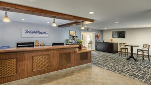 Un espace d’accueil avec un comptoir en bois, une enseigne indiquant « WorldMark by Wyndham », et un coin salon avec une table et des chaises.