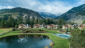 A resort with multiple wooden cabins, a central pond with a fountain, and a swimming pool. - Leavenworth 2BR Mountain Villa – Full Kitchen, Balcony & Near Bavarian Village (Leavenworth)