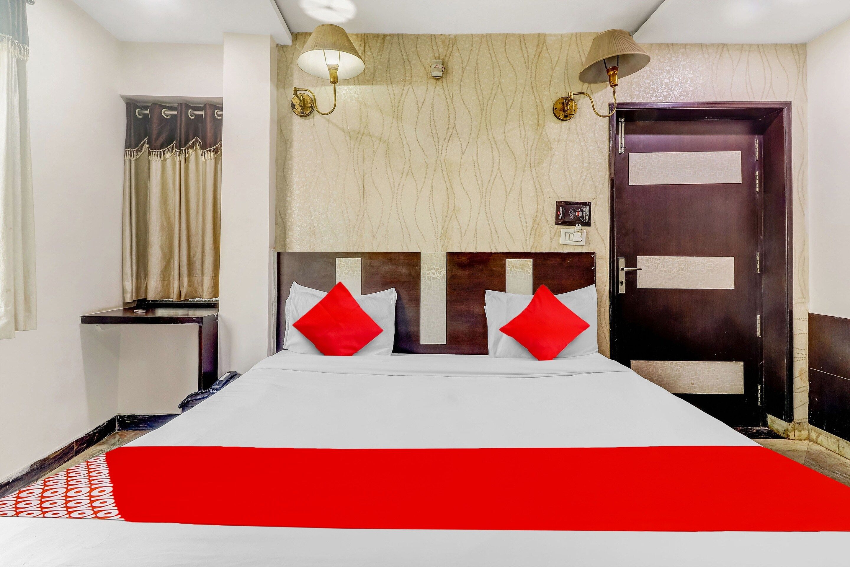 Una habitación de hotel con cama, escritorio, armario y puerta.