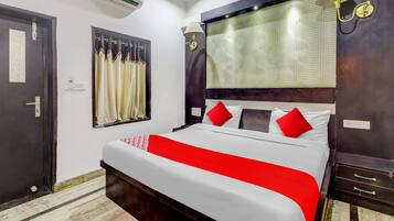 Una habitación de hotel con una cama, una ventana con cortinas, un equipo de aire acondicionado y una mesita de noche.