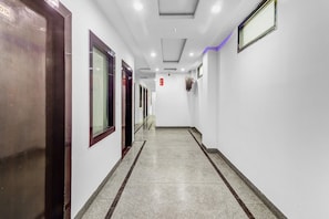 Um corredor com portas à esquerda, alarme de incêndio à direita e hidrante na parede.