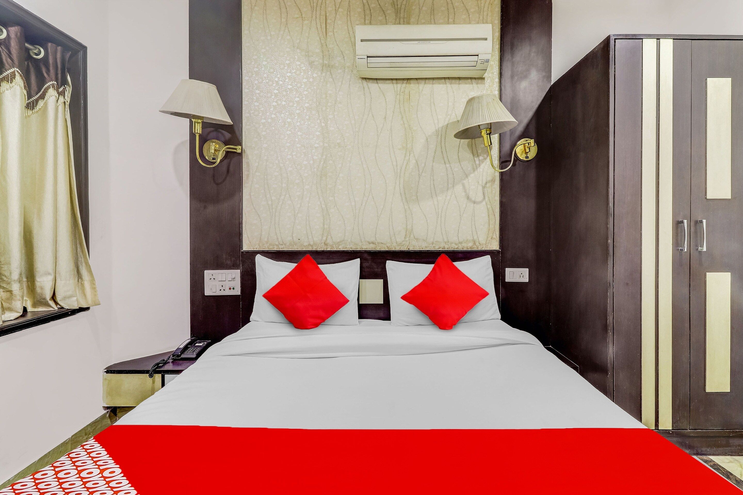 Una habitación de hotel con cama, armario, equipo de aire acondicionado y teléfono.