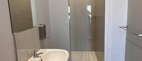 A bathroom with a white sink, a mirror, and a glass-enclosed shower area.