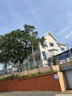 A multi-story building with a brick wall and a metal fence in front.
