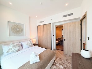Ein Hotelzimmer mit Bett, Nachttisch, Lampe und Blick ins Badezimmer.