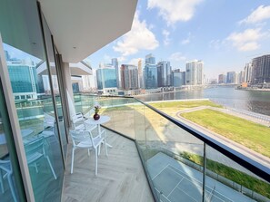 Ein Balkon mit Glasgeländer mit Blick auf einen Fluss und eine Stadtansicht.