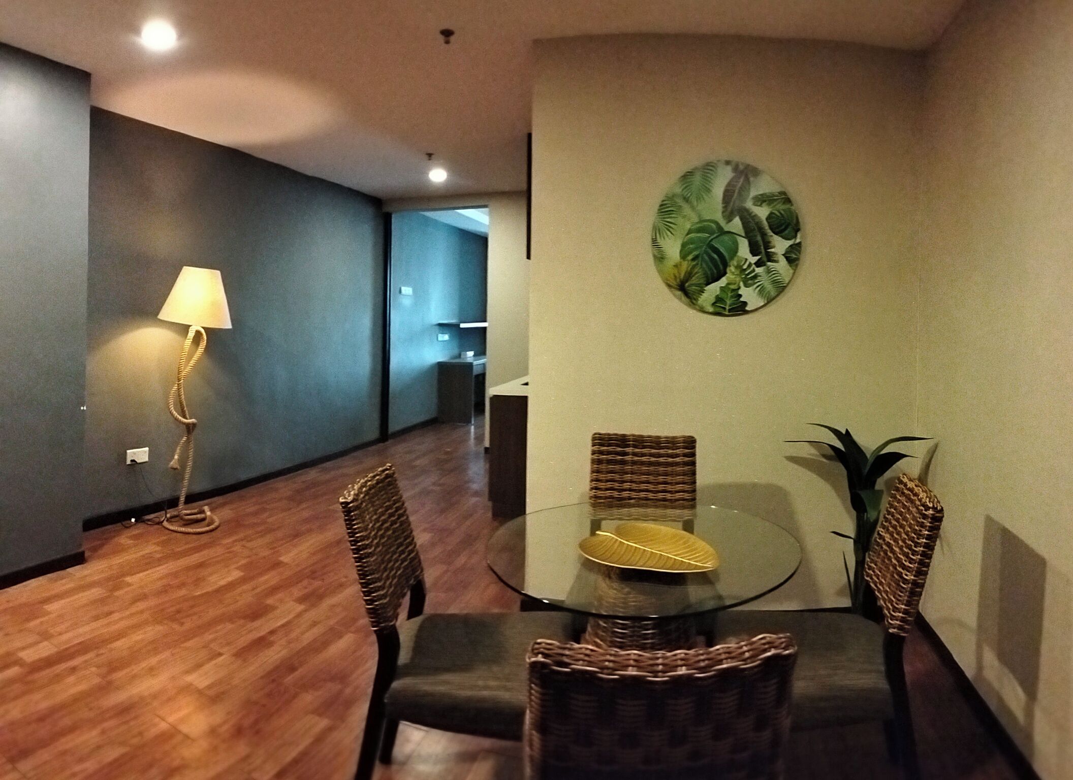 A dining area with a round table, four chairs, a lamp, and a wall art piece.