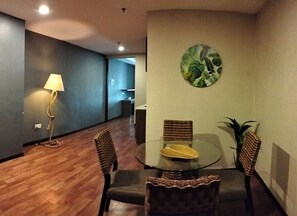 Un comedor con una mesa redonda, cuatro sillas, una lámpara y una obra de arte en la pared.