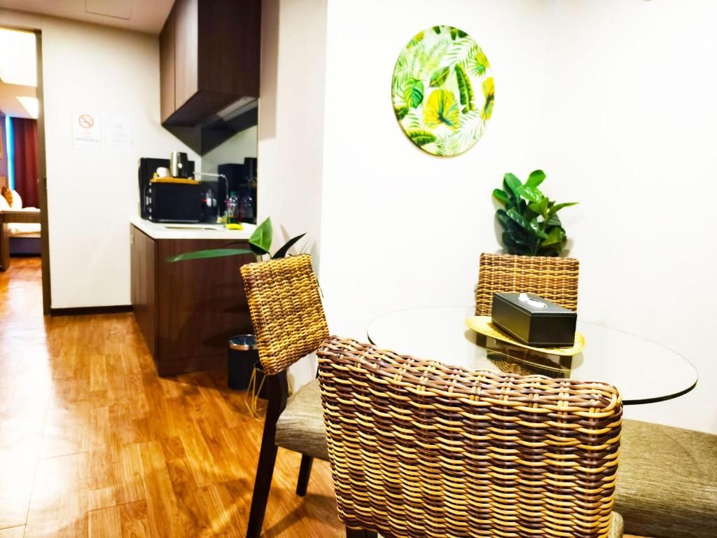 A dining area with wicker chairs, a round glass table, and a wall-mounted plant.