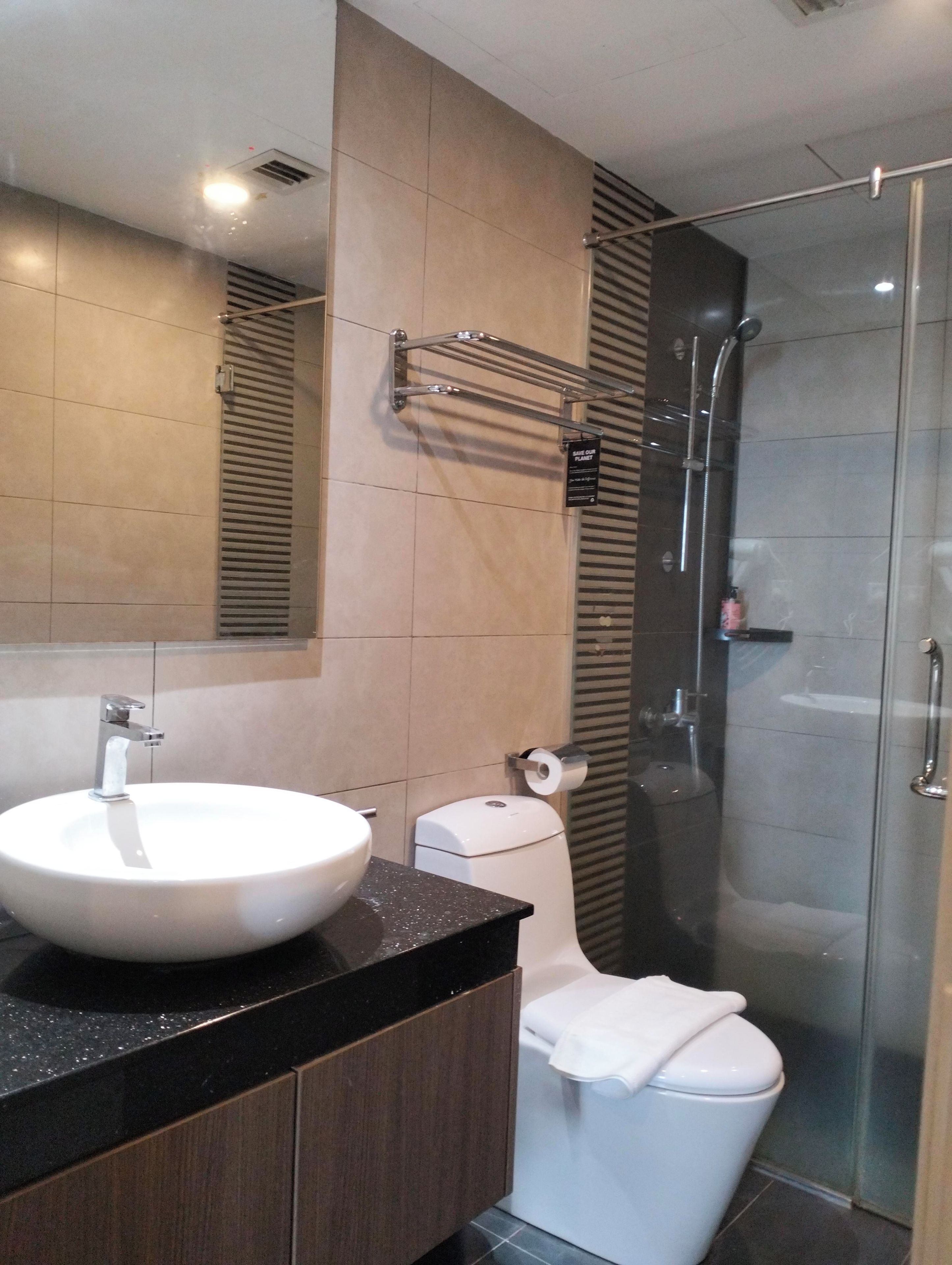 A modern bathroom with a round sink, a toilet, and a glass-enclosed shower.