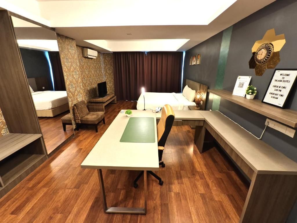 A hotel room with a desk, a bed, a sofa, and a small table. There is a clock on the wall and a sign with check-in times.