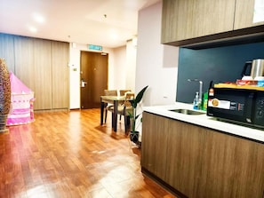 A modern kitchen with wooden cabinets, a microwave, and a sink. - Salaam Suites Shah Alam (Shah Alam)