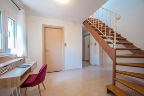 Un interior moderno con una escalera de madera, un escritorio con una silla y una puerta.