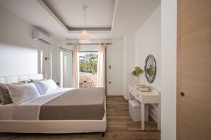 A bedroom with a bed, a desk, and a view of the outside. - Villa Amoudi Private Pool (HERAKLION)