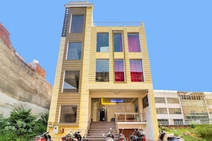 Un edificio de varios pisos con techo plano, una escalera que lleva a la entrada y un letrero que indica 'YOTOWNHOUSE'.