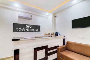 Una mesa de recepción con un cartel que dice 'OYO TOWNHOUSE' y una cámara de seguridad instalada.