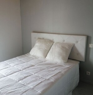 A bed with a headboard, two pillows, and a white bedspread. - Everything within biking distance & absolute comfort: Bright 3-bedroom, 2-bathroom home with an enclosed courtyard (Le Château-d'Oléron)