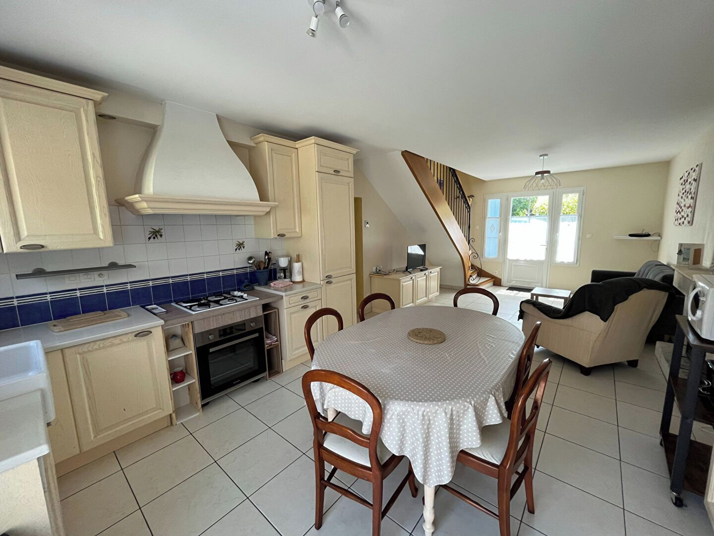 A kitchen with a dining area, a staircase, and a view of the outdoors.