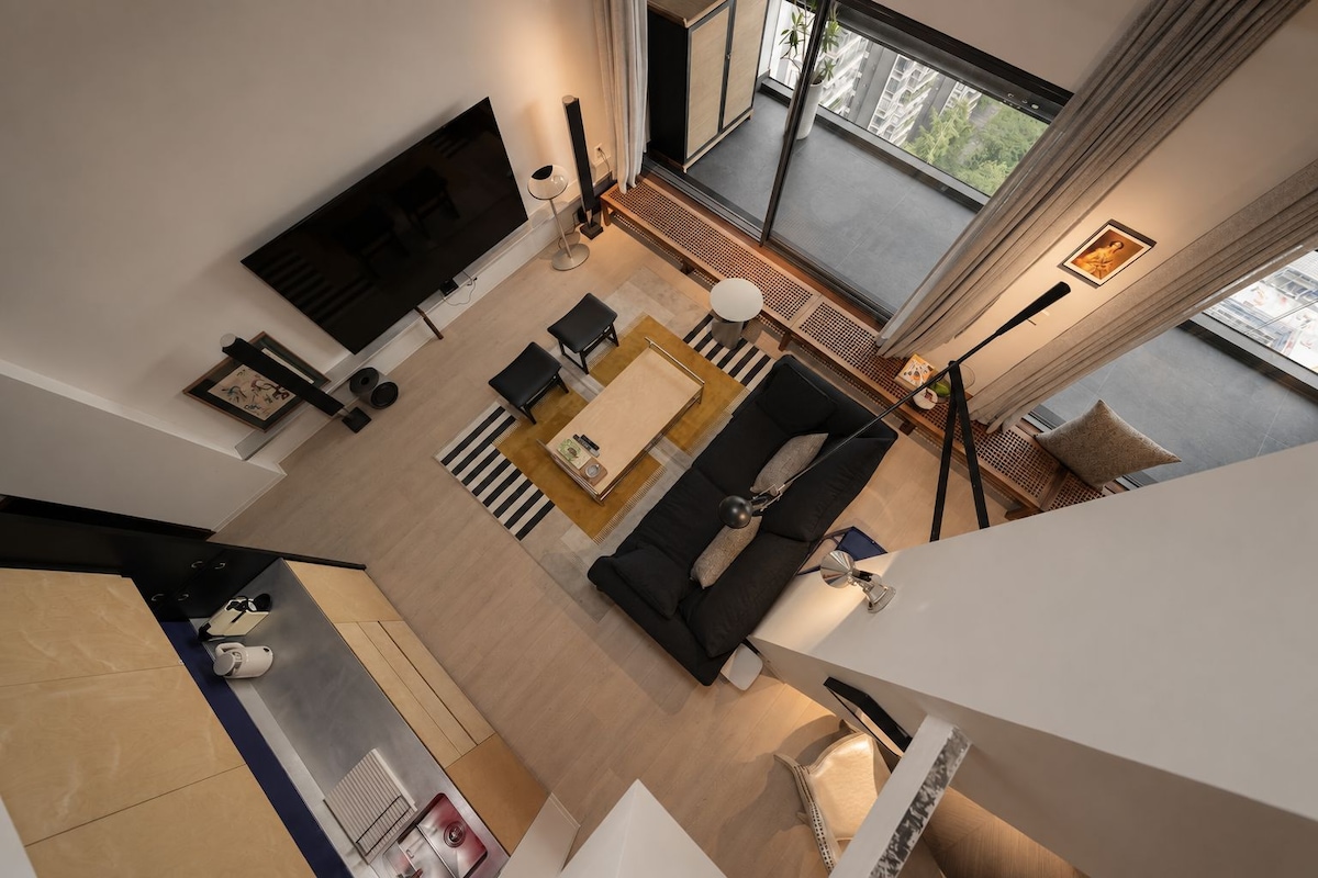 A modern living room with a flat-screen TV, a sofa, a coffee table, and a dining area.
