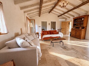 Ein geräumiges Wohnzimmer mit einer Couch, einem Couchtisch und einem Kamin. Es gibt eine Holzkommode mit Geschirr und eine Pendelleuchte.
