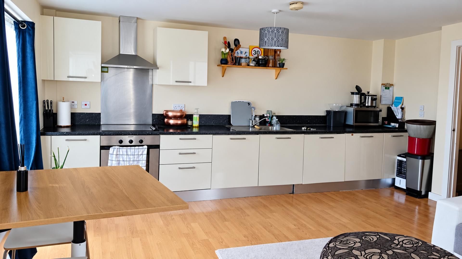 A modern kitchen with a central island, stainless steel appliances, and a hanging light fixture.