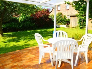 A patio with a brick floor and white plastic chairs. - "rungholtstrasse" (Wyk auf Foehr)