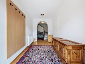 Ein Flur mit einem Holzkasten, einem gemusterten Teppich und einer Heizung.