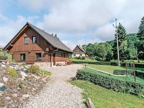 A wooden cabin with a gravel driveway leading to the entrance.