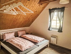A bedroom with a sloped ceiling, a bed with two pillows, a radiator, and a window with curtains. - Wonderful private villa for 18 guests with WIFI, TV, terrace and pets allowed (Česká Třebová)
