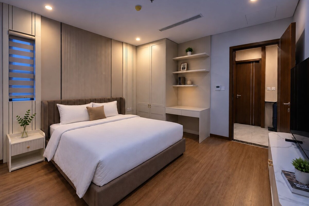 A modern bedroom with a large bed, built-in shelving, a wardrobe, and a television.