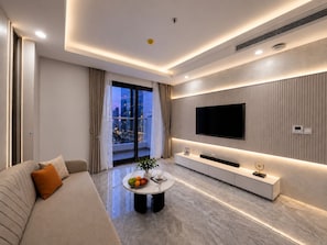 A modern living room with a sofa, coffee table, and a flat-screen TV mounted on the wall. - Nancy Apartment Capital Elite - My Dinh (Hanoi)