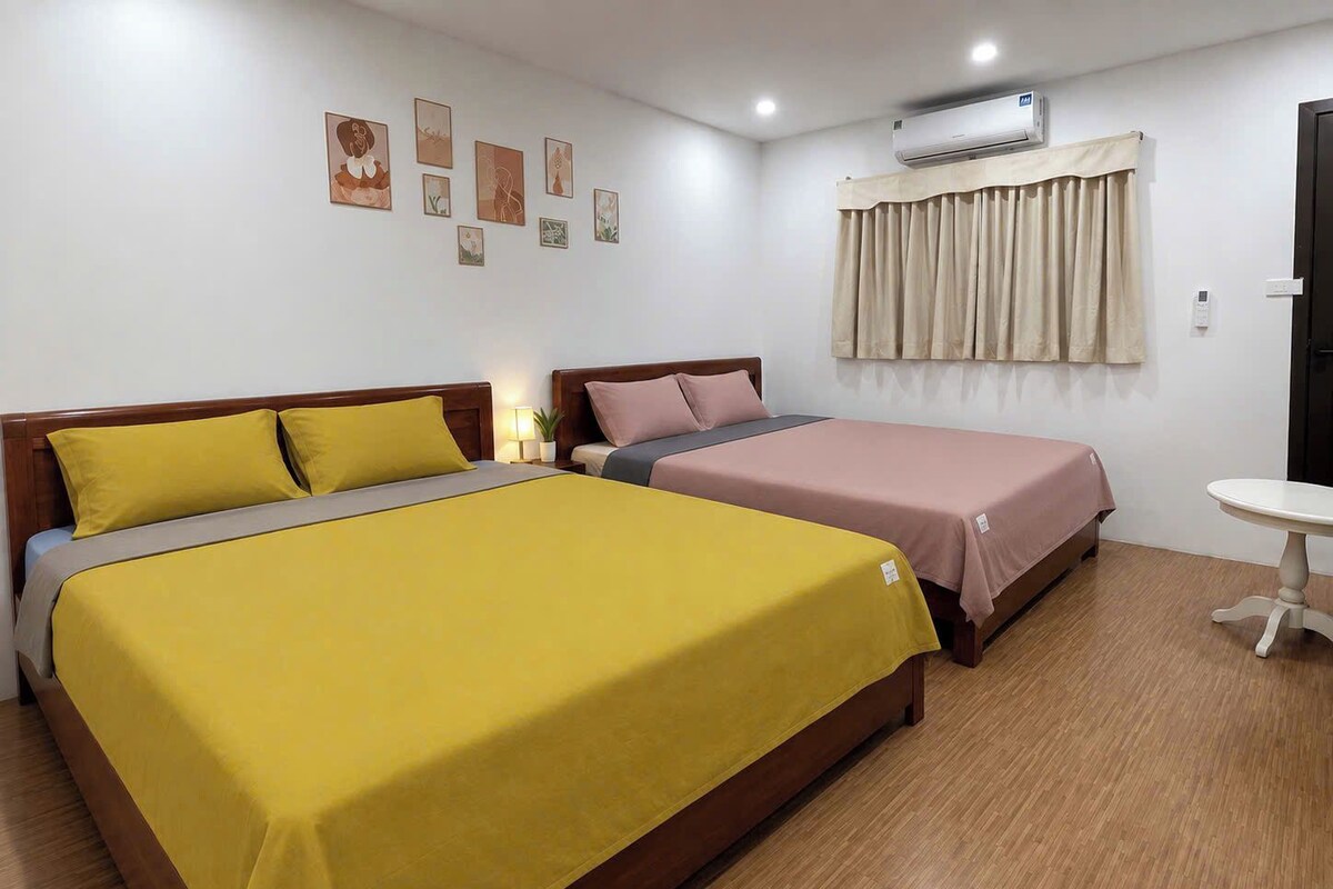 Quarto de hotel com duas camas, uma mesinha e uma obra de arte na parede.