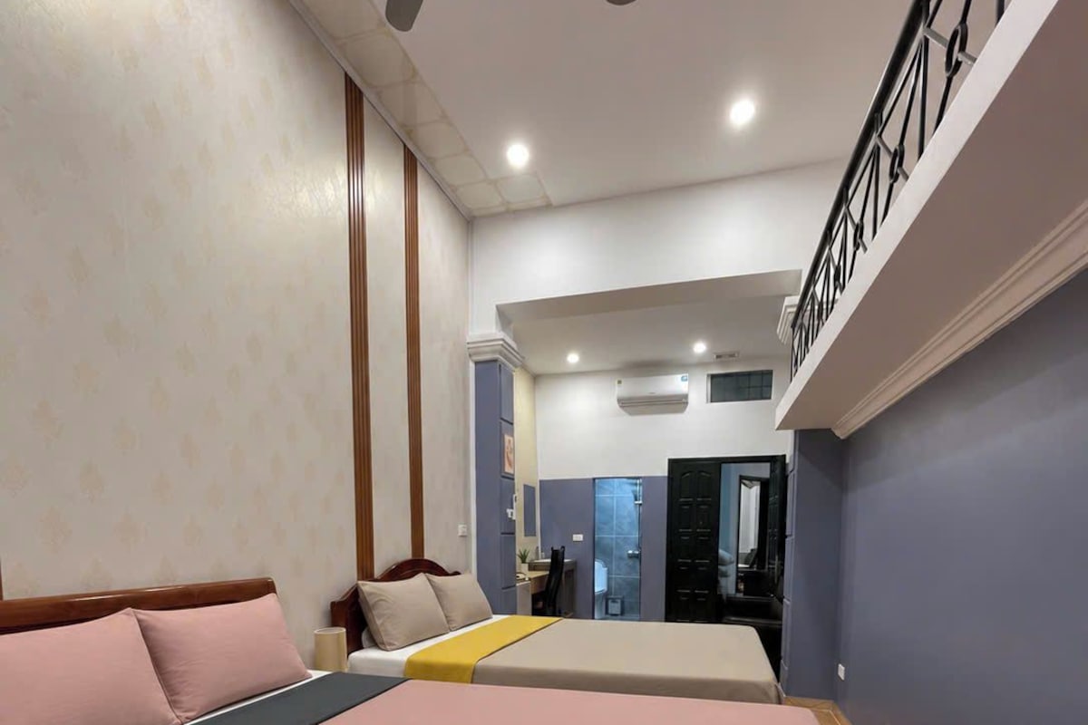 Quarto com uma cama grande, um ventilador de teto e uma escada que dá para um andar superior.