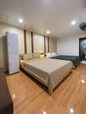 Quarto de hotel com duas camas, geladeira e ventilador de teto.