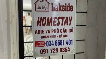 A sign for a homestay named 'HA NOI Lakside' with contact information and address.