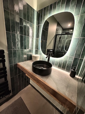 Ein Badezimmer mit modernem Design, das einen runden Spiegel, ein Waschbecken und einen Handtuchhalter zeigt.