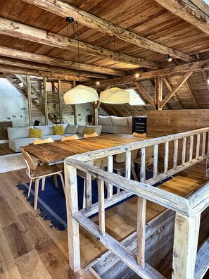 Ein rustikales Interieur mit einem Holzespeisetisch, einer Couch mit Kissen und einer Treppe.